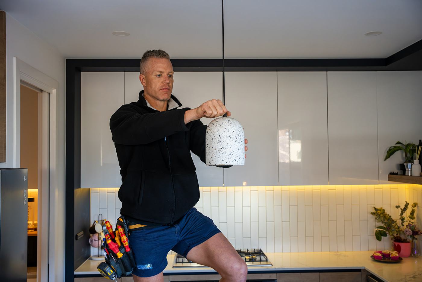 Lance from JAT Electrics installing a pendant light in a kitchen