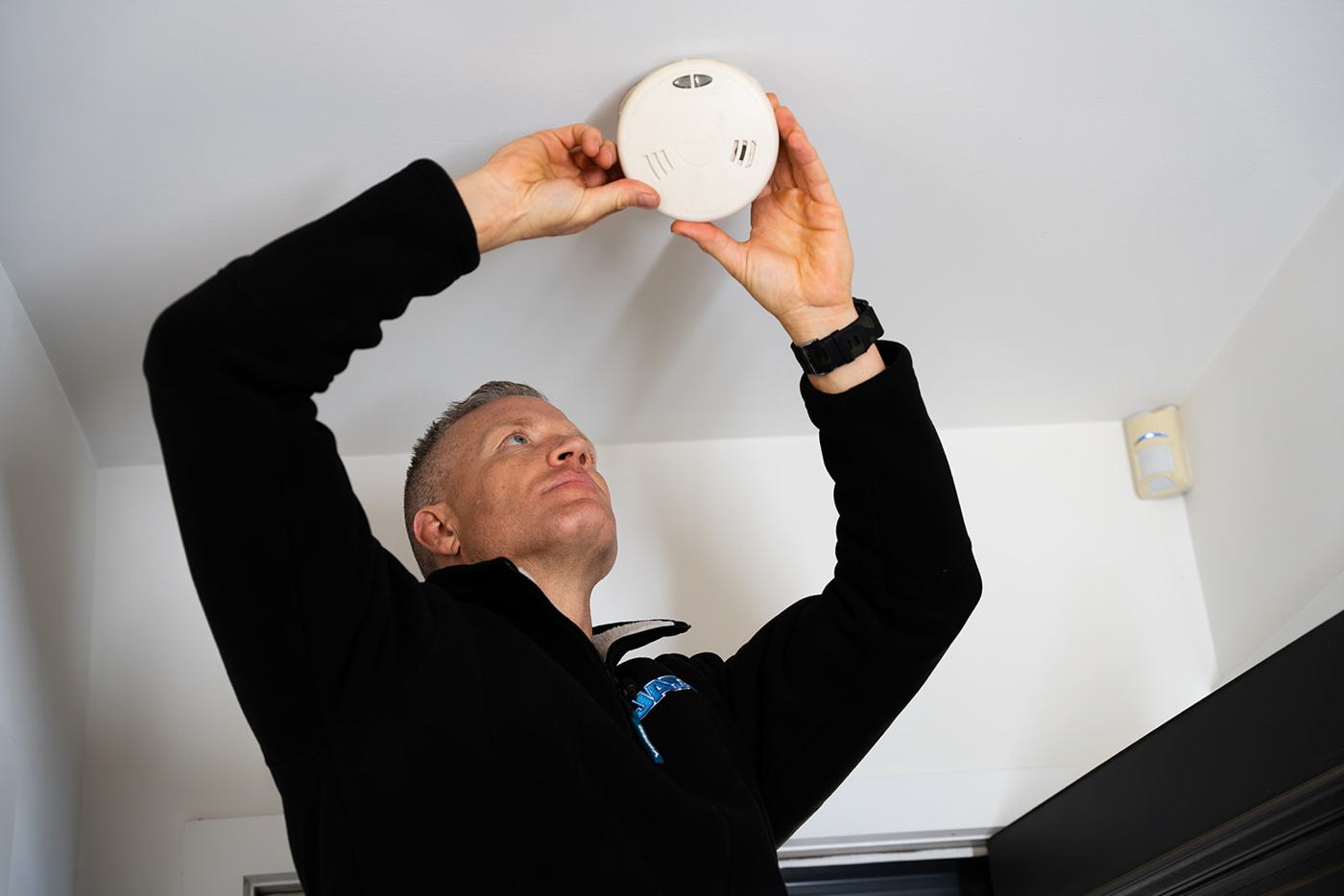 JAT Electrics electrician fitting a smoke alarm to a ceiling